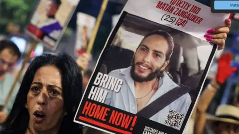 Gaza talks to focus on releasing all hostages in one go, Netanyahu hints JACK GUEZ/AFP via Getty Images Enav Zangauker holds a portrait of her kidnapped son, Matan, during an anti-government protest calling for action to secure the release of Israeli hostages held captive in Gaza.