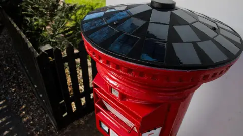 Solar-powered postboxes are being rolled out across UK Royal Mail A view of black solar panels that cover the entire lid of the red postbox