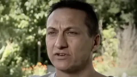 Police killed in Australia shooting named as manhunt continues Nine/A Current Affair Dezi Freeman is photographed. He has dark hair and stands in front of a garden.