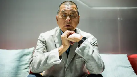 Who is Jimmy Lai, the HK media tycoon on trial for national security crimes? Getty Images Jimmy Lai, in a gray suit and black pants, poses for a photograph during an interview with AFP news agency in Hong Kong