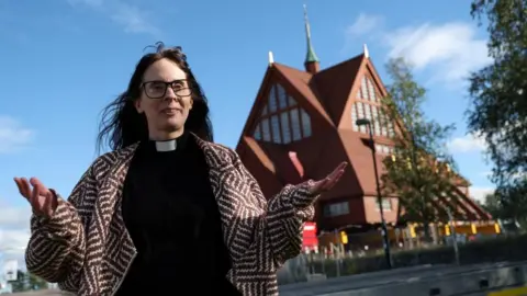 Entire church begins two-day journey across Swedish city of Kiruna Reuters Pastor Lena Tjarnberg, speaks during an interview in front of Kiruna's historic wooden church, before it is moved to its new site