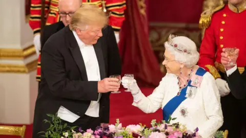 Ed Davey to boycott banquet over Gaza Getty Images Donald Trump raises a glass with Queen Elizabeth II during a state banquet as part of his 2019 visit to the UK. He wears a formal black suit, white shirt and bow tie, while she wears a white, long-sleeved dress, silver crown and a ruby and diamond necklace. The pair are touching wine glasses and appear to be attended by two footmen.
