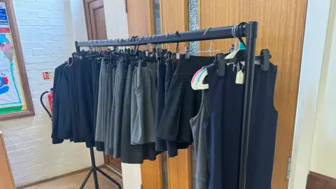 Free school uniform bank in Suffolk 'vital' say parents George King/BBC A rail filled with school uniform items.