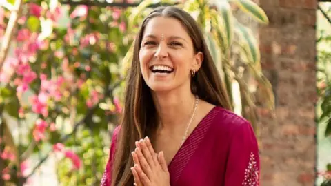 Is super skinny back? UK sees rise in complaints over thin models Instagram/MissCharHolmes Charlotte Holmes smiles with her mouth open while sitting on a yoga mat, with her long brown hair over her shoulder and her hands pressed in a prayer position while she wears a purple dress