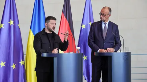 Trump shifts ceasefire stance and urges Ukraine to agree Russia peace deal Getty Images German Chancellor Friedrich Merz and Ukrainian President Volodymyr Zelensky stand next to each other at podiums as they attend a joint press conference at the Chancellery following a virtual meeting hosted by Merz between European leaders and US President Donald Trump