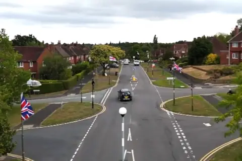 The questions about St George's and union jack flags lining British streets Union Jack and St George flags hang from every lamppost on a street in Birmingham, seen from an aerial drone shot.