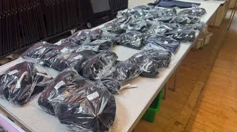 Free school uniform bank in Suffolk 'vital' say parents George King/BBC A table with bagged-up school uniform items on it