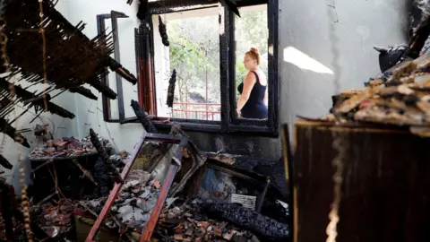 Wildfires rage across southern Europe as temperatures pass 40C Reuters A woman in a black sleevless dress looks passes by the burnt out shell of her home in Piperi Village, Montenegro.