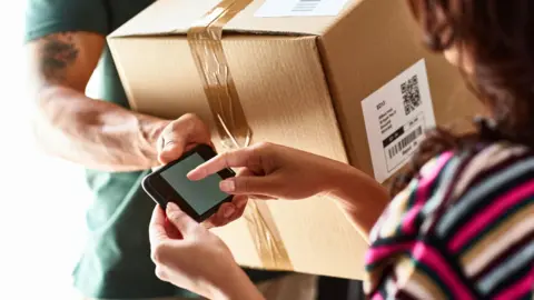 Value of small packages sent from China to UK more than doubles Getty Images A delivery man in a green t-shirt hands a brown cardboard box to a woman with brown hair, wearing a stripy top. The delivery man is holding a phone up for the woman to sign for the package.