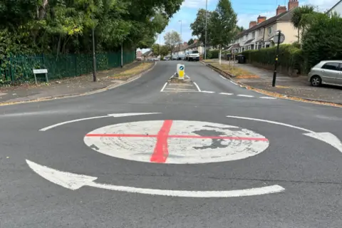 The questions about St George's and union jack flags lining British streets A red cross of St George spray painted onto a mini white roundabout on a residential street.
