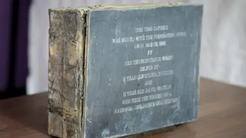 Princess Diana 90s time capsule contains Kylie CD and pocket TV Great Ormond Street Hospital for Children A lead-encased wooden box is on the table. On the outside, there is information written about the date of its burial.