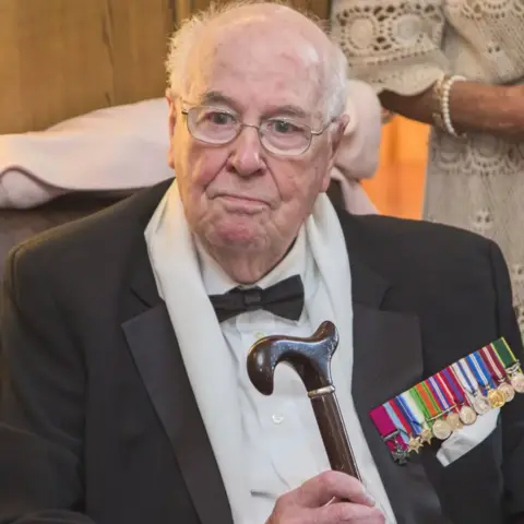 Aberdeen man who was last surviving WW2 Victoria Cross recipient dies aged 105 Berry Vissers/Squadron Prints An older John Cruickshank in recent years. He is looking slightly off camera. The top of his head is bald with white hair round the side. He is wearing light-framed glasses and a black suit jacket over a white shirt with a black bow tie. He has a collection of colourful medals on his upper left chest and is holding a walking stick in his right hand.