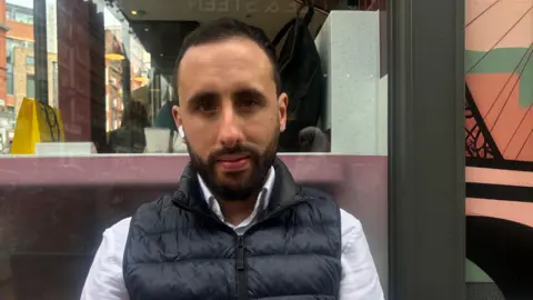 How coffee chains like Costa lost the matcha generation Rafik with short black hair and short beard wearing a black puffer gillet over a white shirt and sitting outside a coffee shop with one bluetooth headphone in his right ear