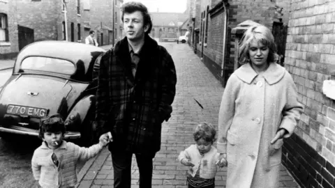 Ray Brooks, voice of Mr Benn, dies aged 86 A black-and-white still image of Cathy Come Home, in which characters Reg and Cathy walk along an urban street holding the hands of two small children.