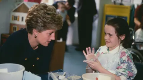 Princess Diana 90s time capsule contains Kylie CD and pocket TV Getty Images Princess Diana, wearing a blue Chanel suit, speaks to a young girl playing with play-doh. The girl, who is looking at Diana, is wearing a floral jumper and has a sphere of play-doh in her hands.