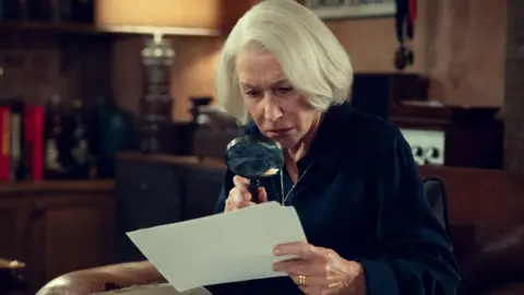 Pierce Brosnan felt 'huge responsibility' towards fans of the book Netflix Dame Helen Mirren in The Thursday Murder Club, looking at a piece of paper through a magnifying glass