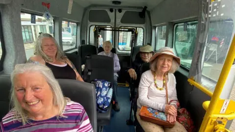 Call for free bus travel to help under-22s into work Jane Bishop Five elderly people in a minibus, looking at the camera and smiling