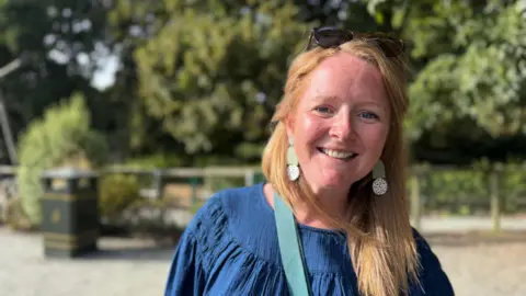 Summer holiday childcare costs a struggle, Guernsey parents say Woman in her 30's with long ginger hair. she is in a denim blue top and big earrings