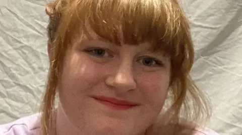 Under-22s join call for free travel Maisy Moazzenkivi Maisy Moazzenkivi with her short red hair tied up smiling at the camera and wearing a pink t-shirt
