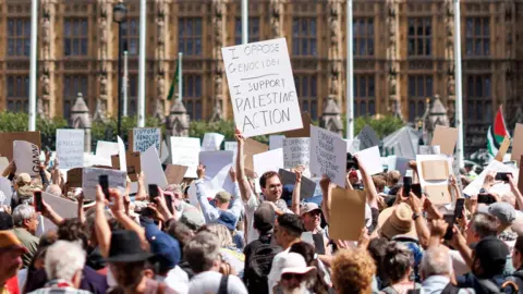 Sally Rooney says she will support Palestine Action despite ban EPA Protestors at Parliament Square holding up placards saying I oppose genocide, I support Palestine Action
