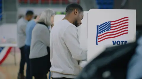 Newsmax settles Dominion election defamation case for $67m Getty Images Voters casting their votes at a US election polling station