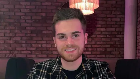 Microsoft boss troubled by rise in reports of 'AI psychosis' Supplied by interviewee A smiling young man in a checked shirt