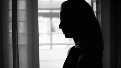 NCA to investigate South Yorkshire Police officer abuse claims Getty Images A woman cast in monochrome shadow stands by a window.