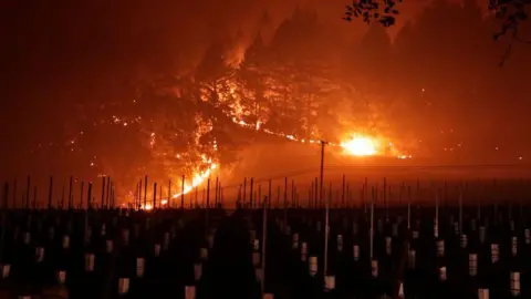 Climate change pushing winemakers to blend different years Getty Images A large wine fire burns at night behind a vineyard in California's Napa Valley