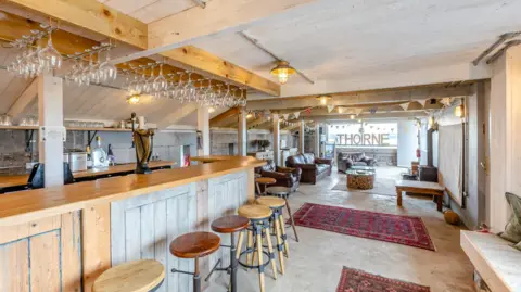 Pembrokeshire's Thorne Island fortress turned into £3m party space Strutt & Parker A bar area created in the fortress. The bar itself is wooden, with wooden and metal bar stools and wine glasses hanging from the ceiling on wire racks. Beyond, Afghan rugs cover parts of the concrete floor, with leather armchairs and a window looking out to the sea.
