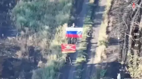 Ukraine admits Russia has entered key region of Dnipropetrovsk Russian ministry of defence A fuzzy image of two men holding Russian flags on a road - one of the flags is a tricolour the other is a red military flag