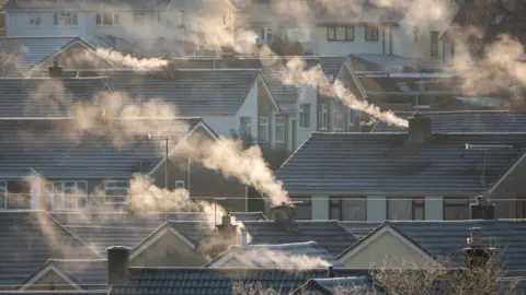 Energy prices expected to rise ahead of winter Getty Images Steam or smoke comes from chimneys on roofs of a number of houses on a frosty day.