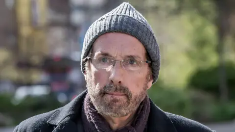 Ex-priest Chris Brain found guilty of 17 indecent assaults PA Media A man in his sixties wearing a grey bobble hat, dark winter jacket, a mauve scarf and glasses. He looks pensively just to one side of the viewer. He has a short beard and moustache.