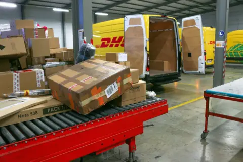 How US shoppers will be hit as the tariff exemption ends AFP via Getty Images Boxes covered in tape and shipping labels are piled up in a DHL shipping facility.