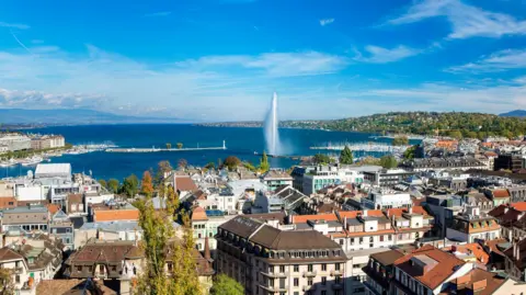 Confusion and anger in Switzerland Getty Images Geneva skyline cityscape with an aerial view of Jet d'eau fountain, Lake Leman, bay and harbour from the bell tower of Saint-Pierre Cathedral. Sunny day blue sky.