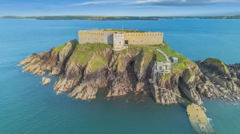 Pembrokeshire's Thorne Island fortress turned into £3m party space Strutt & Parker An aerial view of Thorne Island, with the yellowed fortress walls encompassing it and cliffs covered in greenery at its edges. The island is surrounded by the sea, with the mainland in distance. Two flights of steps lead down to the water's edge.