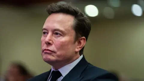Musk firms sue Apple and OpenAI, alleging they hurt competition Getty Images Elon Musk seen in profile in suit and tie in November 2024.