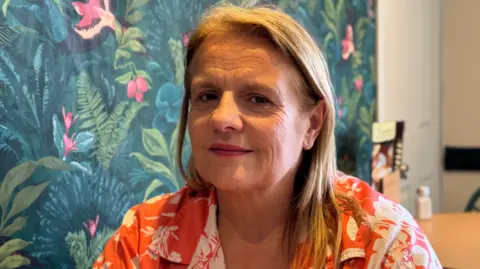Tamworth cafe owner feared £24k E.On energy bill would sink firm BBC Samantha Panton smiling for the camera. She is in her cafe. There is flowery wallpaper behind her. We can see a menu and some salt and pepper shakers blurred out in the background. She has long blonde hair and is wearing a colourful pink and white top.