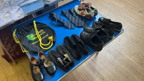 Free school uniform bank in Suffolk 'vital' say parents George King/BBC A blue table with school shoes and trainers on it.
