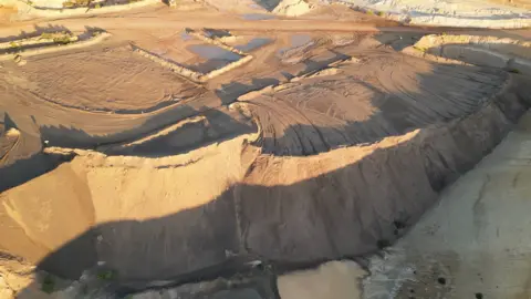 Australia bid to take on China dominance Iluka Resources stockpile can be seen from above. It looks like piles of sand in what appears to be a rocky desert.