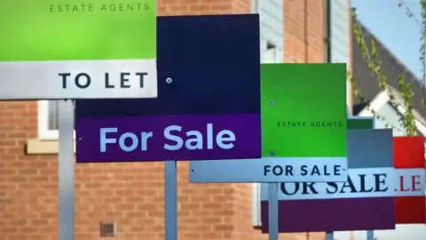 BBC Generic For Sale and To Let Estate Agent signs lined up outside a new build housing and flats estate development
