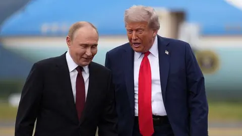 Kremlin plays down Zelensky talks as Trump warns Putin may not want 'to make deal' Getty Images Vladimir Putin and Donald Trump pictured side-by-side on the tarmac of an airbase with a large blue aircraft blurred in the background. The men are mid-conversation and leaning in towards one another. Both are wearing dark suits with white shirts. Putin wears a maroon tie while Trump's is bright red. Trump also wears a pin of the US flag on his lapel.