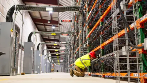 Data centres to be expanded across UK as concerns mount Getty Images A technician in a high-vis jacket and hard hat kneels on the floor of a warehouse, fixing computer wiring on a series of racks towering above them.