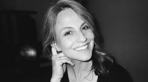 Lives torn apart by fatal crashes on the A9, Scotland's longest road Chris Strong Katie Bastion-Strong, smiles in a black and white image, looking into the camera while her hand is held behind her ear.