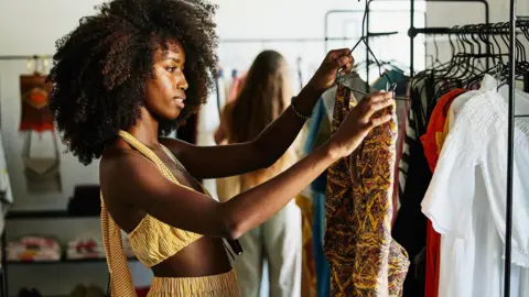 How US shoppers will be hit as the tariff exemption ends Getty Images A shopper inspects a a vibrant, patterned outfit she has picked out from a clothes rack. She is dressed in a striped yellow outfit.