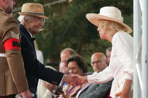 The WW2 veteran who moved Queen Camilla to tears PA Media Yavar Abbas (left) smiles as he shakes hands with Queen Camilla (right)