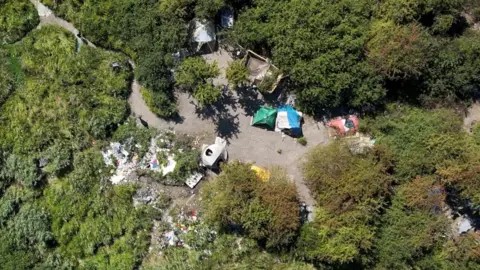 'Is my secret camera working?' Camp viewed from a drone from above. A few tents in a forest clearing.