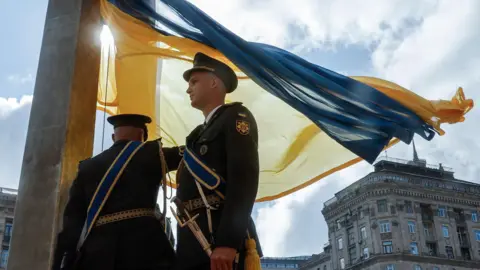 Zelensky vows to continue fighting as Ukraine marks independence day EPA Two servicemen from the Ukrainian Guard of Honor raise the blue and yellow national flag in downtown Kyiv on 23 August 2025.