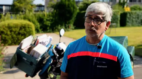 Denmark's state postal service calls time on letter deliveries Postman Herman Moyano standing in front of his scooter motorbike