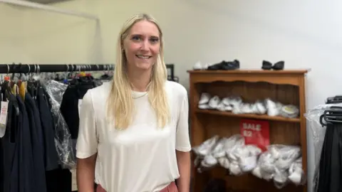 'Less of a stigma' on second-hand school uniforms woman in front of school uniform sale
