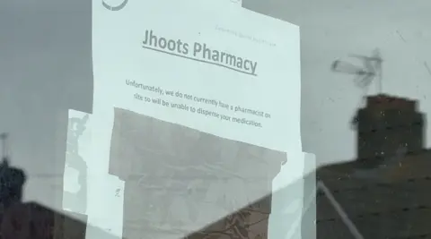 'Shocking' Jhoots pharmacy chain should be shut down, says MP An A4 sheet of paper is taped to the inside of a glass door. It reads 'Jhoots Pharmacy' in big, bold and underlined letters at the top. In smaller type, it then says "Unfortunately, we do not currently have a pharmacist on site so will be unable to dispense your medication."